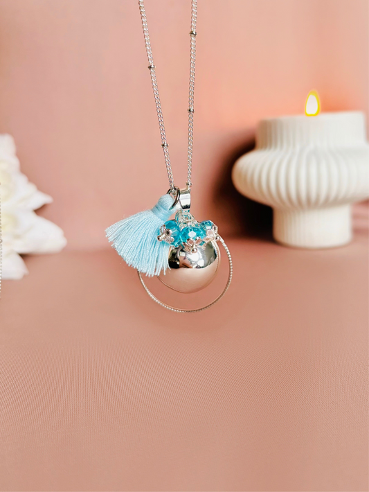 Bola de grossesse argent avec chaîne satellite. Le bola de grossesse se compose d'un pompon bleu ciel, sur le bola sont accrochés de jolis cristaux bleu ciel, le tout entouré d'un cerceau en acier inoxydable.