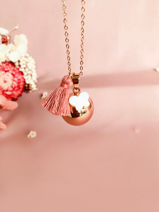 Bola de grossesse or rose et breloque en nacre en forme de papillon montée sur une chaîne or rose et d’un pompon rose