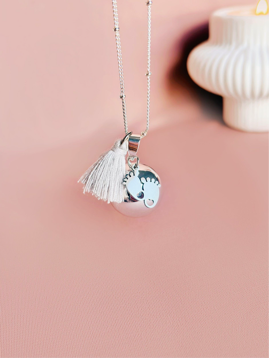 Bola de grossesse en argent avec pendentif petits pieds et pompon en coton montée sur une chaîne satellite