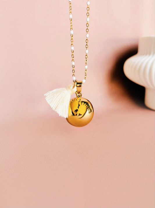 Bola de grossesse Alma or avec pendentif en forme de petit pieds et pompon coloré au choix. Bijou de maternité élégant.