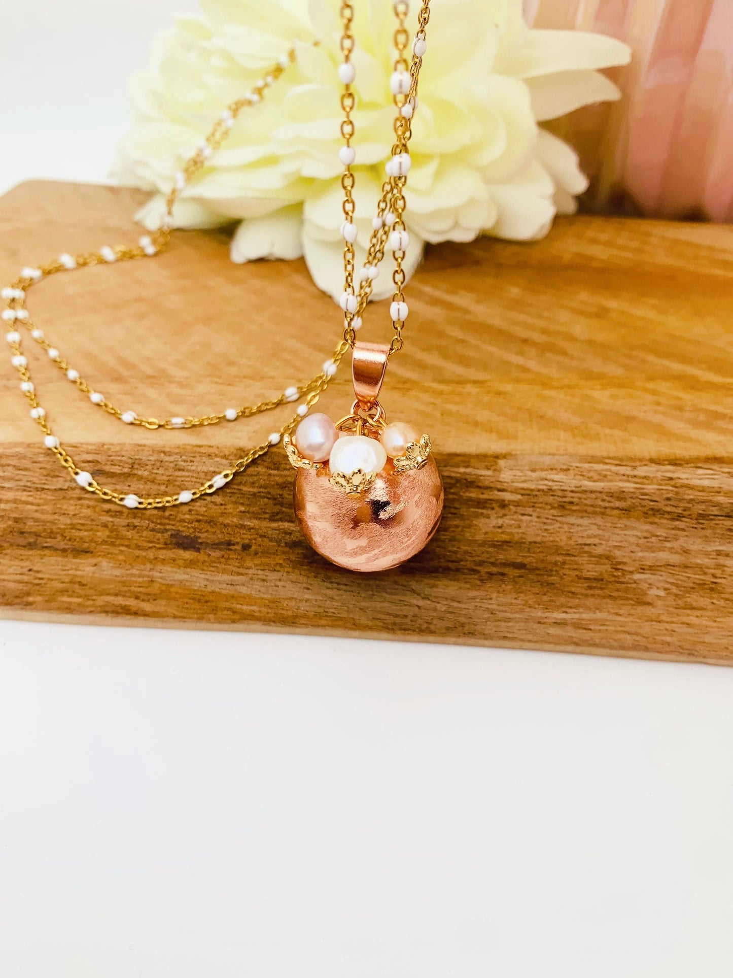 Bola de grossesse or rose brossée et petites perles d’eau douce.
Montée sur une chaîne en résine blanche.